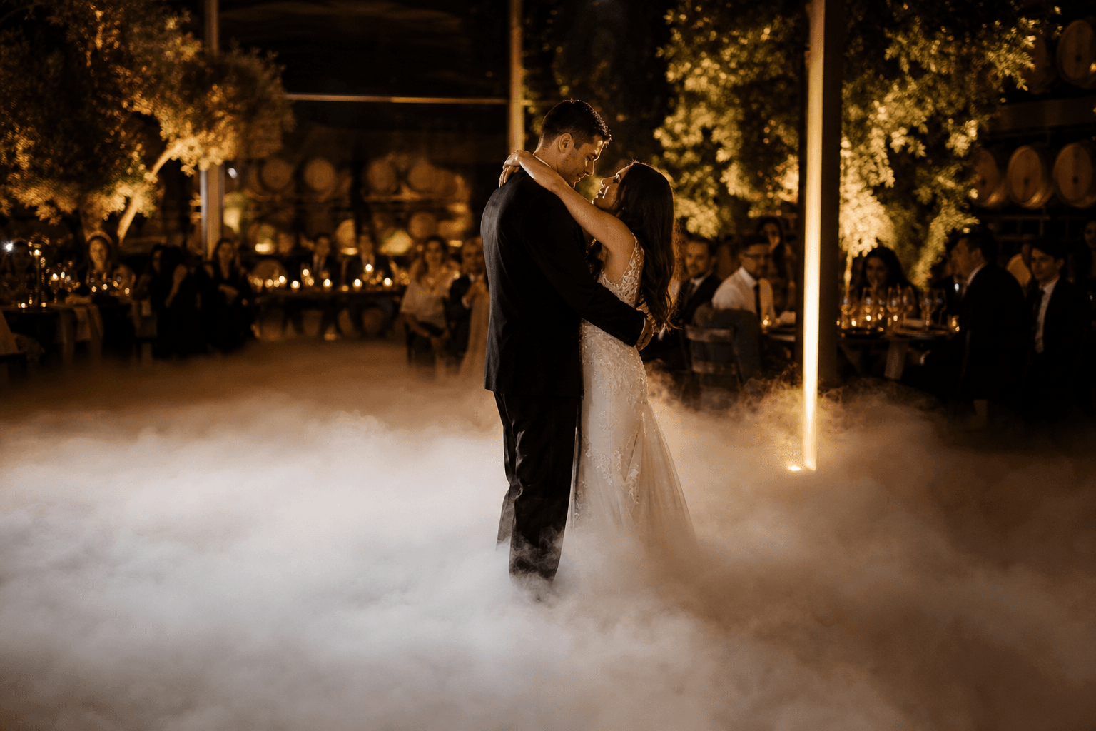 A couple dancing in a reception room with low white fog covering the floor around them